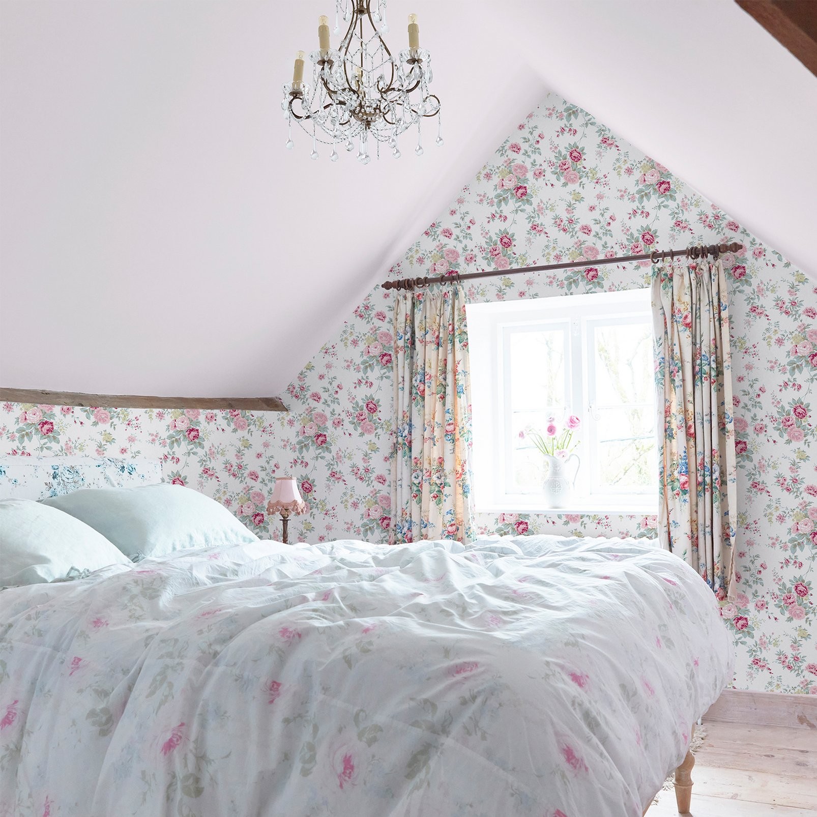 Wild Flower Wallpaper features a delicate floral pattern in soft pink and green on a white background, enhancing a cozy bedroom with light blue bedding and elegant curtains.