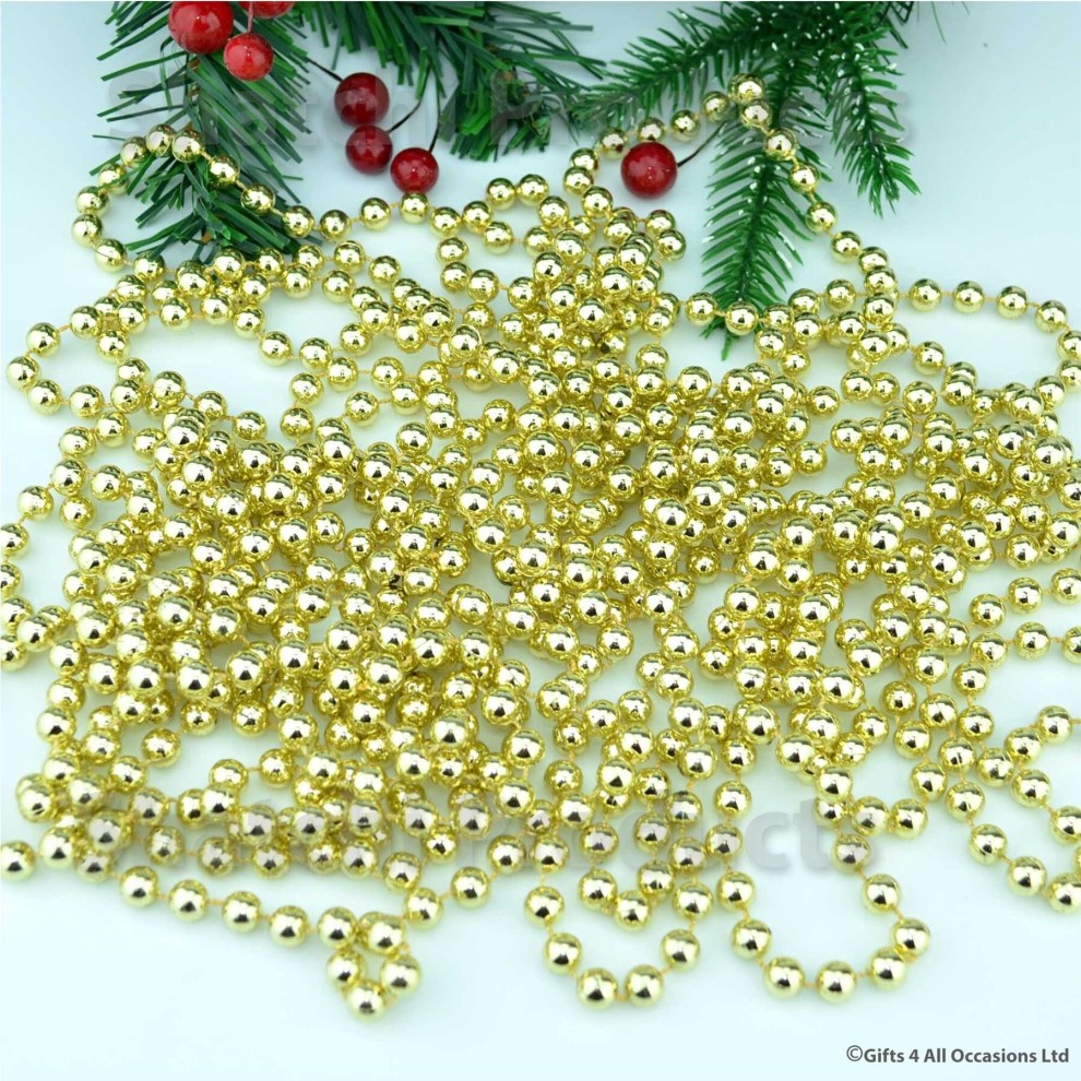 Shiny gold 24ft hanging bead garland made of plastic, featuring round beads, perfect for Christmas tree decorations and festive parties, with greenery and red berries in the background.
