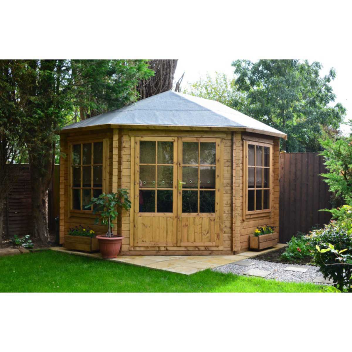A wooden corner log cabin with 28mm interlock cladding, featuring a sloped grey roof, large windows, double doors, and surrounded by greenery and planters.