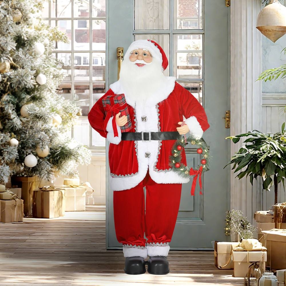 Musical animated Santa Claus in a red suit, holding a gift and wreath, with white beard and glasses, standing in a festive room with a Christmas tree and wrapped presents.