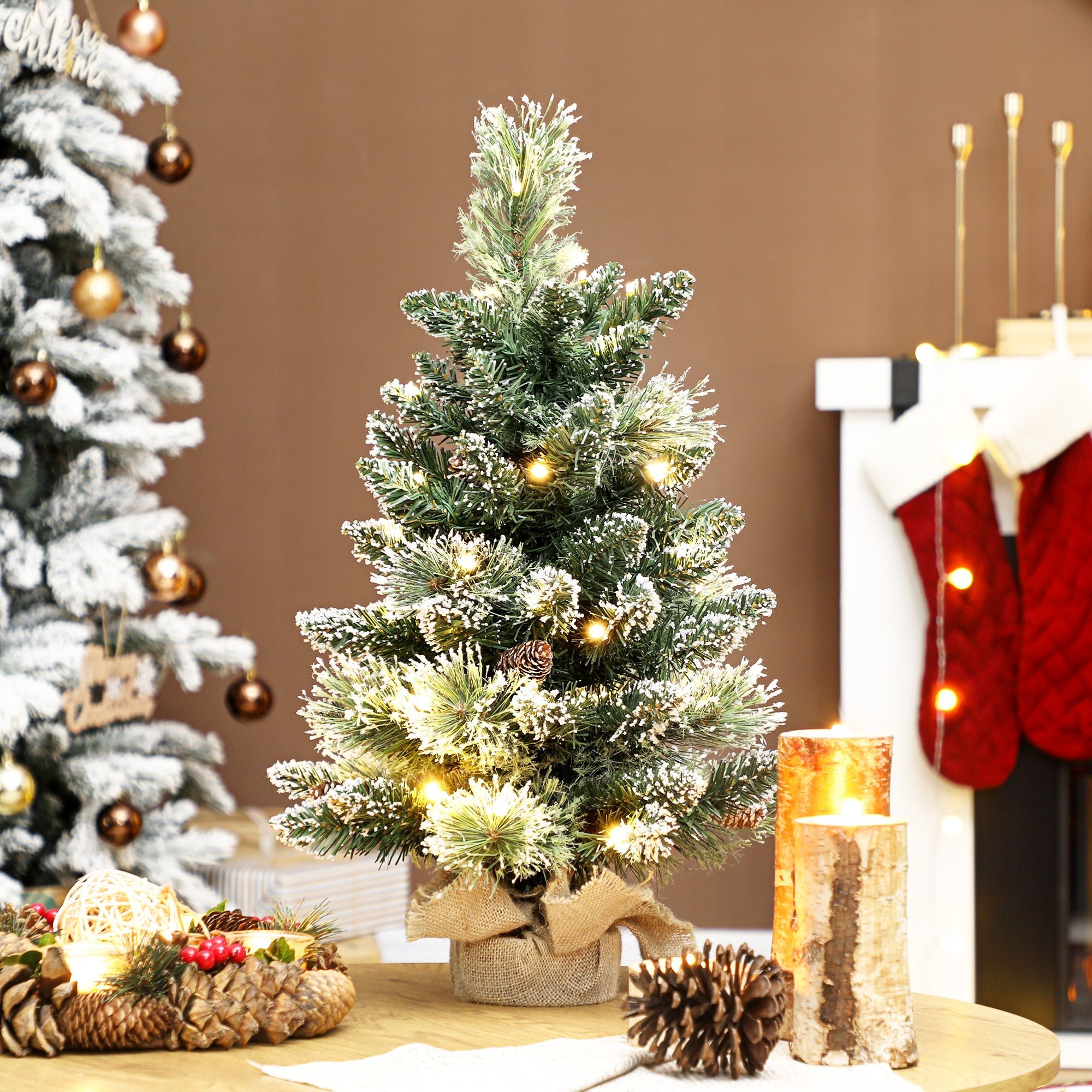 Mini tabletop Christmas tree, 60 cm tall, snow-flocked green branches, adorned with warm white lights, set in a burlap base, surrounded by festive decor.