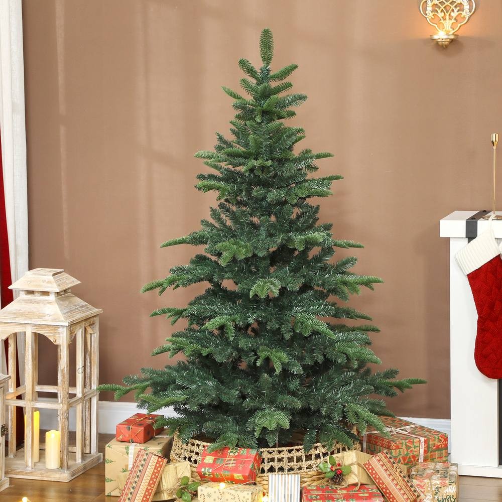 5ft green hinged Christmas tree with realistic branches, surrounded by wrapped gifts and a decorative lantern, set against a warm-toned wall.