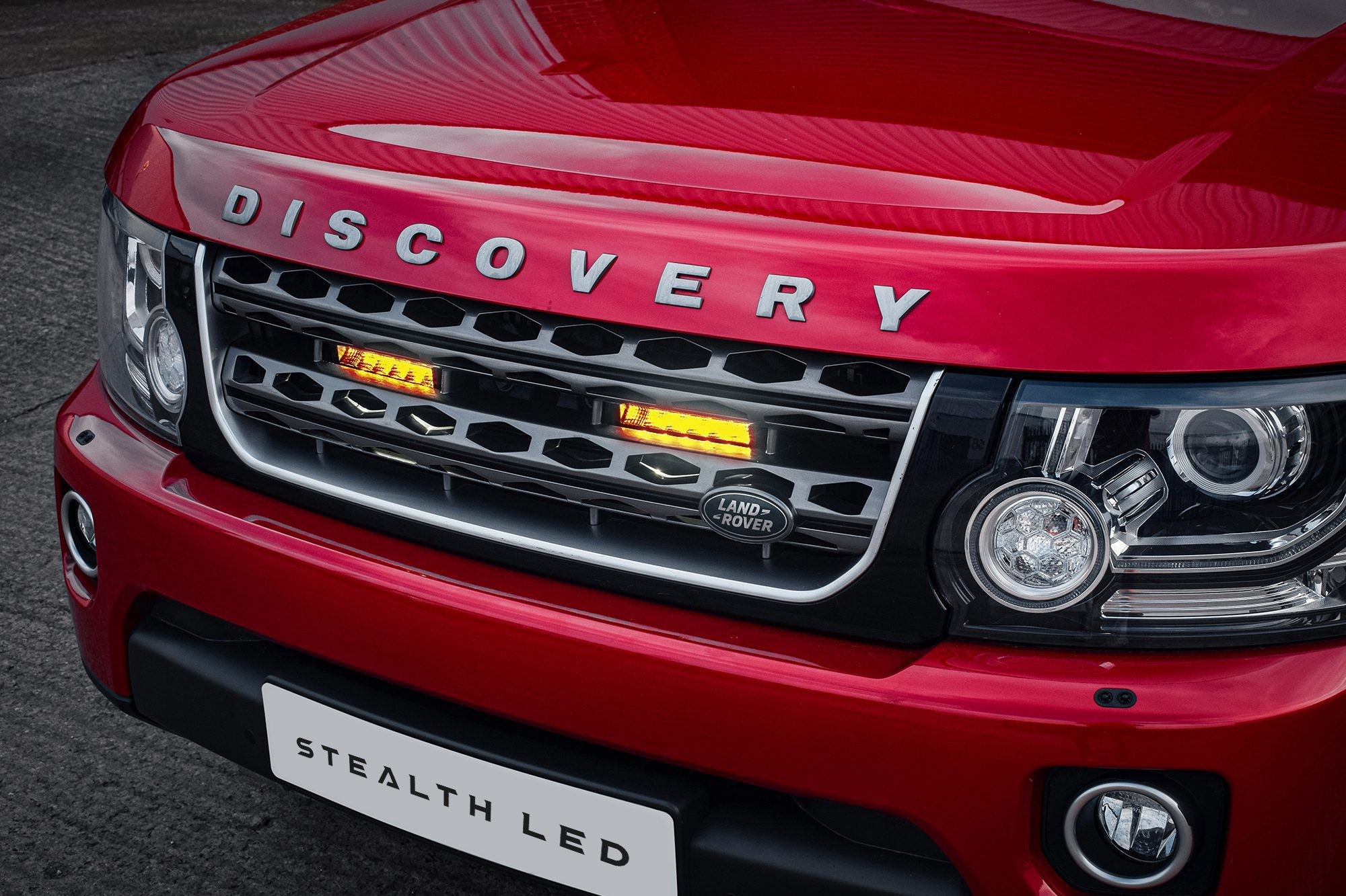 Red Land Rover Discovery 4.5 with a sleek black grille featuring twin 6-inch flashing luminous LED lights, showcasing a modern design and high visibility.