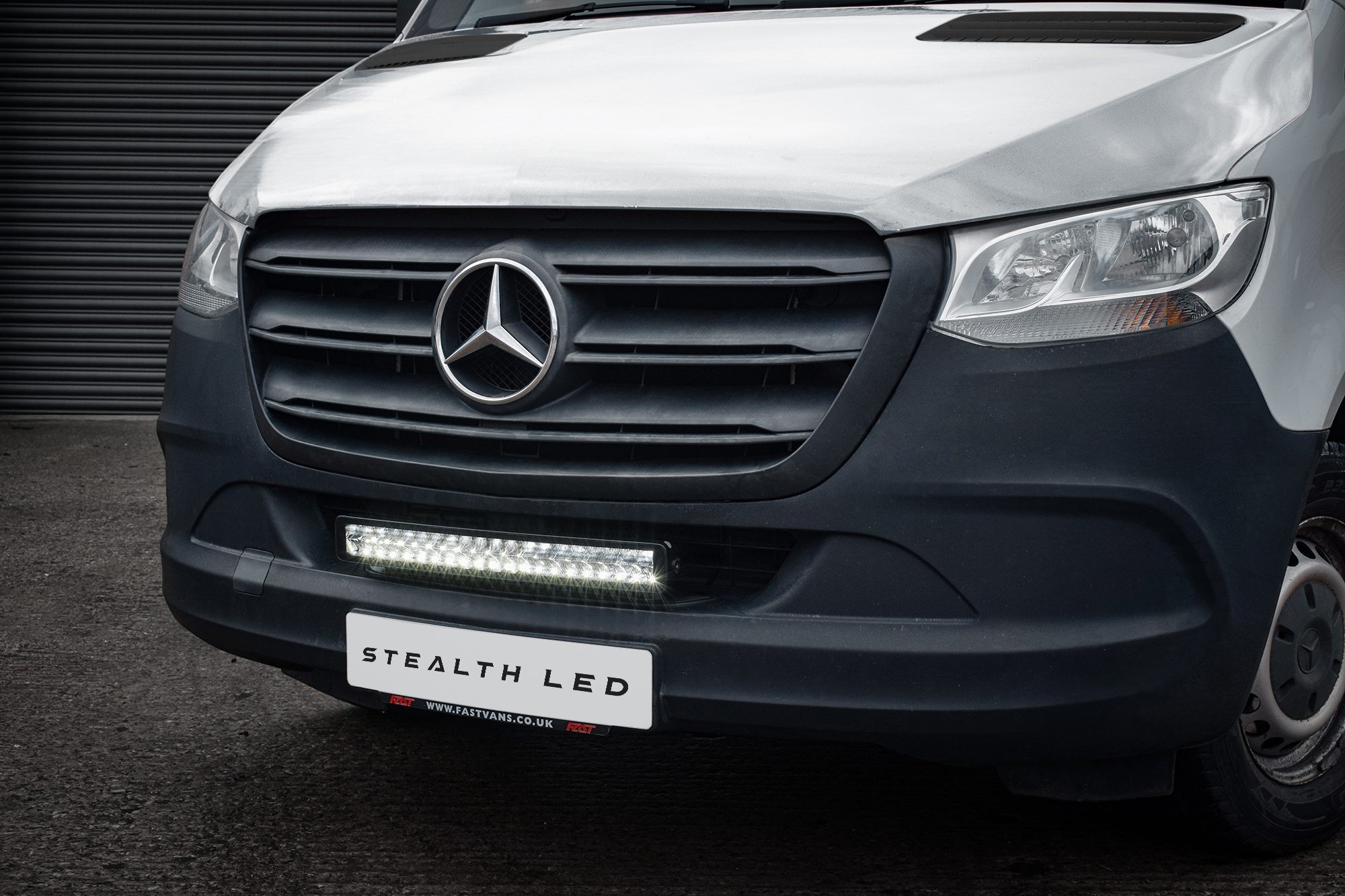 Luminous LED integration grille kit for a 2019+ Mercedes Sprinter, featuring a sleek black grille with a bright white LED light bar beneath, showcasing a modern design.