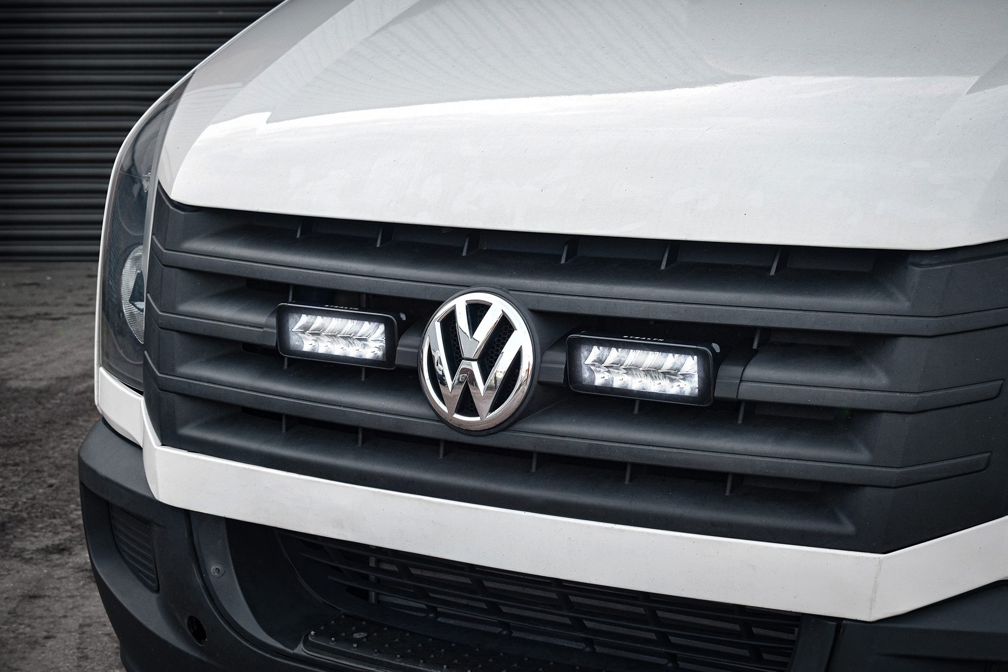 Twin 7" luminous LED lights integrated into the front grille of a white VW Crafter, featuring a black grille and prominent VW logo, designed for high visibility with 10,080 lumens.