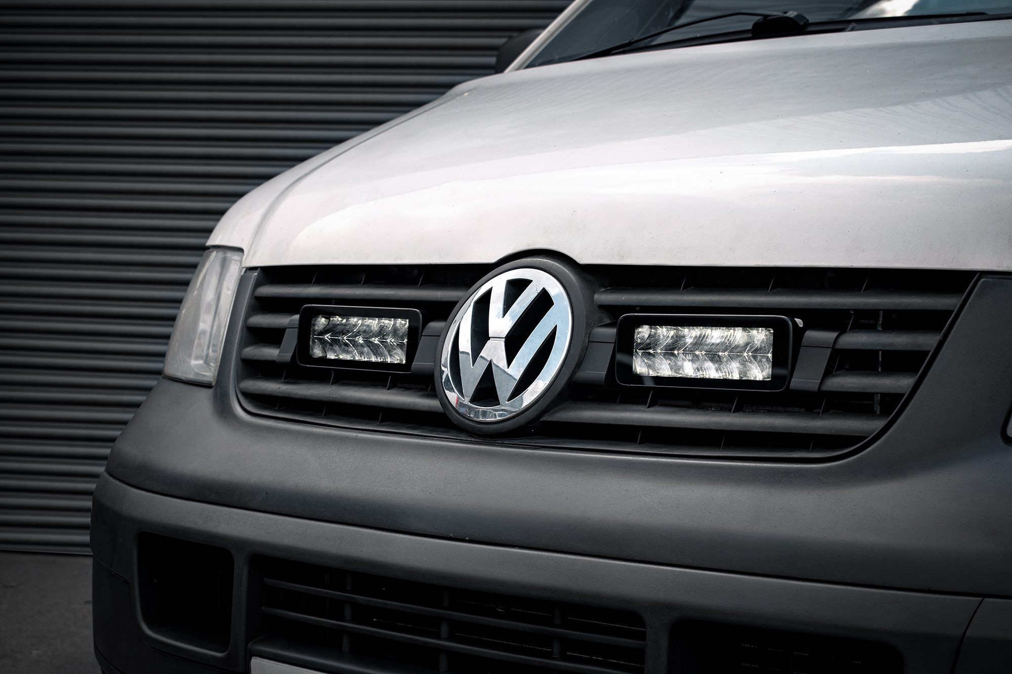 Luminous LED integration kit for VW Transporter T5, featuring twin 7" lights, sleek black housing, and a prominent VW logo on a silver and black front grille.
