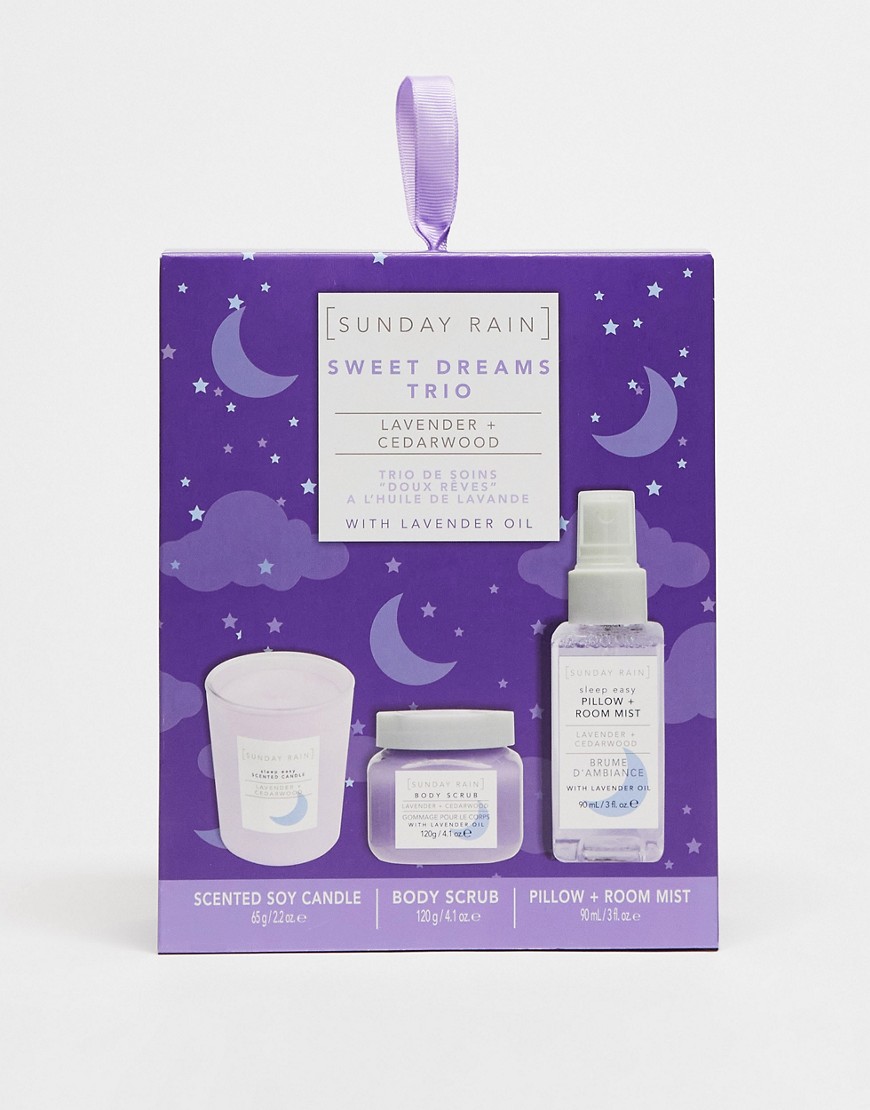 Lavender and cedarwood gift set featuring a scented soy candle, body scrub, and pillow/room mist, all in purple packaging with calming designs.