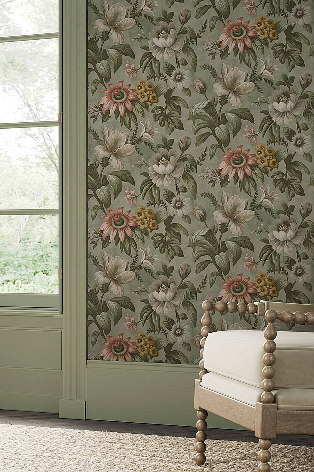 Floral wallpaper featuring large sage green flowers with pink and yellow accents, set against a muted green background, complementing a light beige upholstered chair.