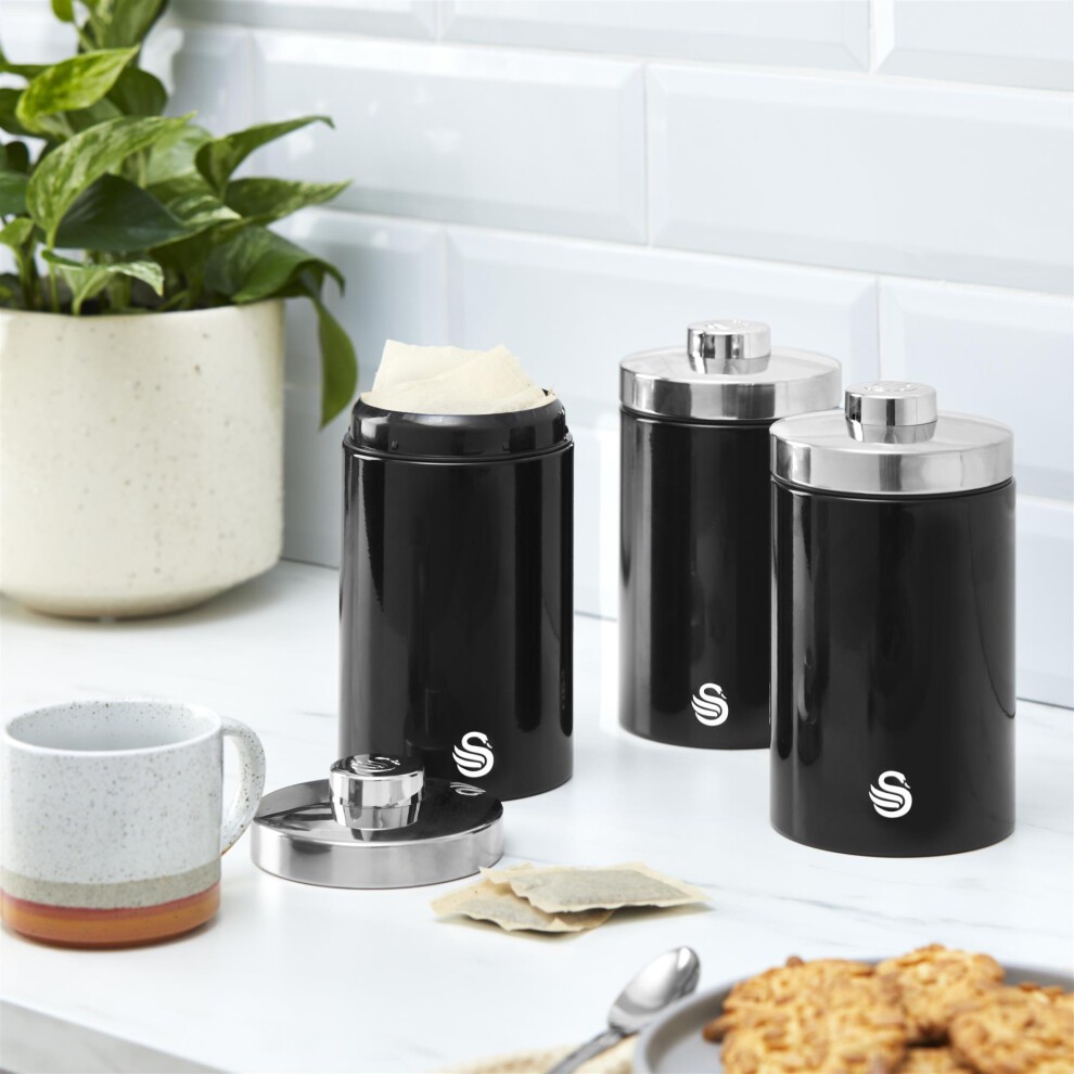 Black Swan bundle featuring three sleek canisters with silver lids, a stylish mug, and a potted plant on a marble countertop.