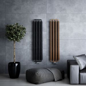 Terma Ribbon Copper Powdered Vertical Designer Radiator in a warm copper finish, featuring sleek vertical bars, mounted on a textured gray wall, alongside a potted plant and a gray cushion.