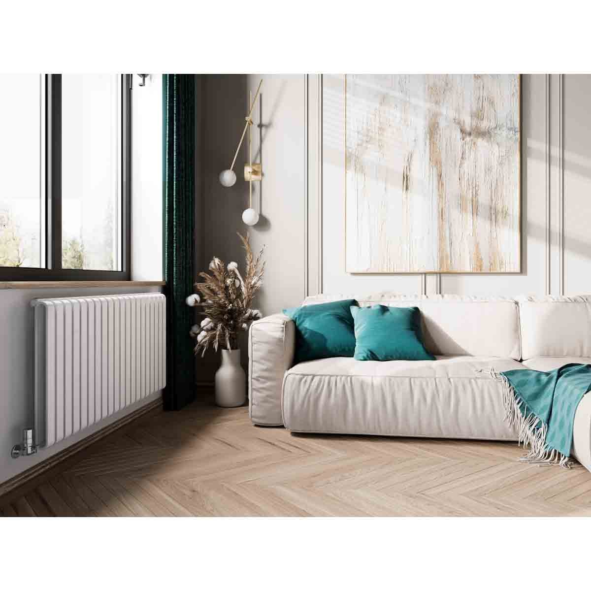 Terma WARP-room radiator in soft matte white, 630x1305mm, features a sleek, modern design, positioned beside a light-colored sofa with teal cushions in a bright, stylish room.