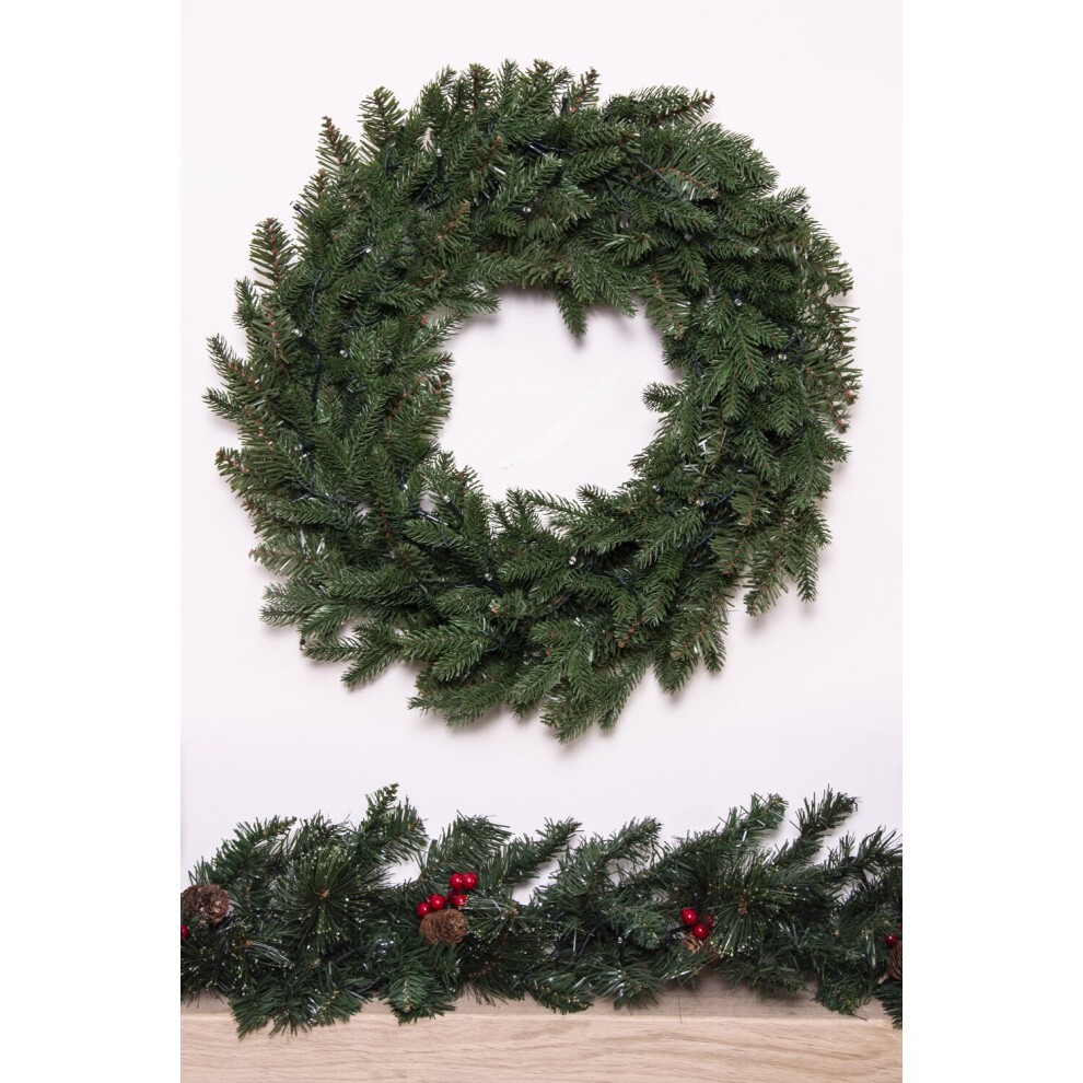 A lush green pine wreath measuring 60cm, featuring realistic foliage with subtle hints of red berries and pinecones, perfect for festive decor.