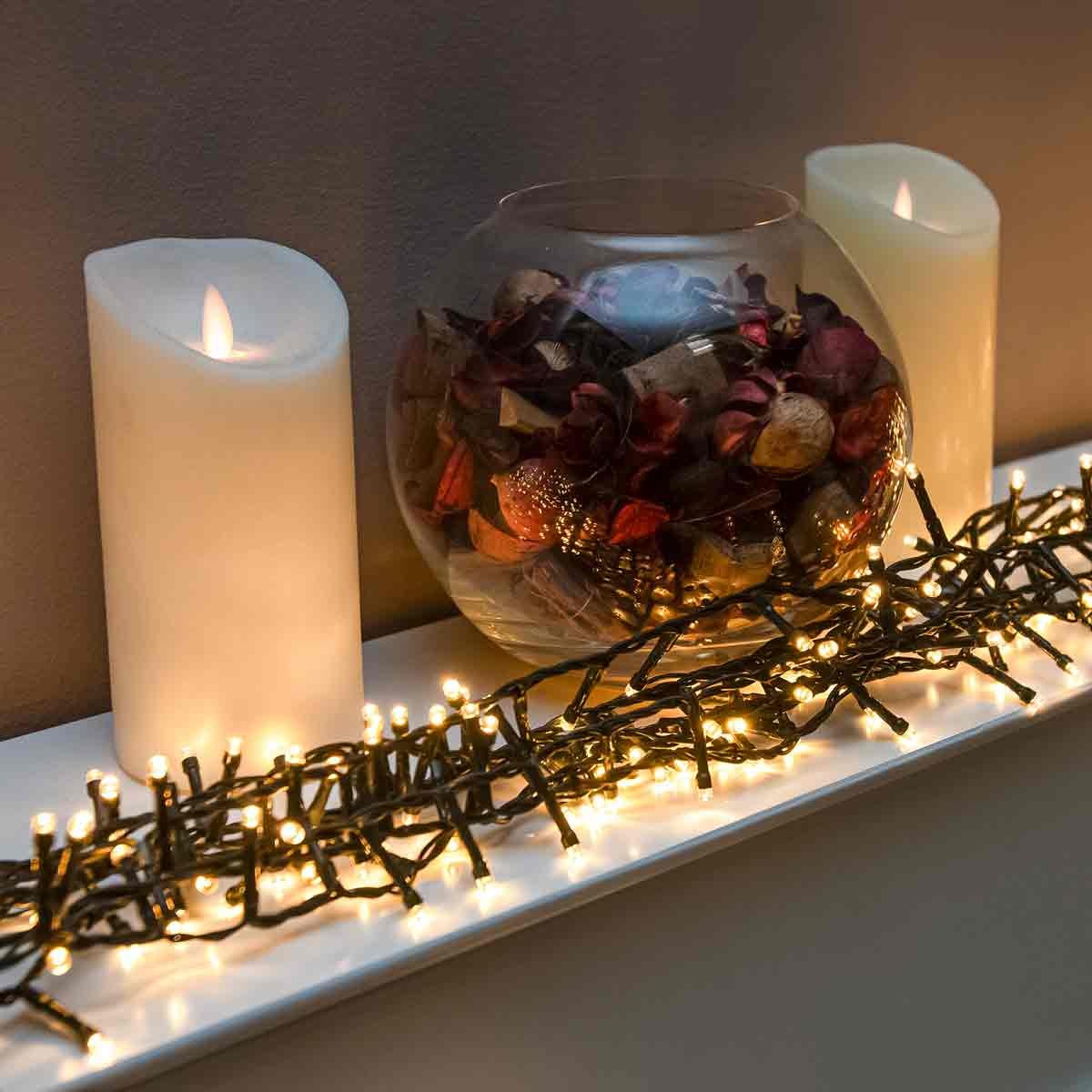 240 LED warm white Christmas string lights with a green cable, displayed alongside a glass bowl of decorative items and two white flameless candles.