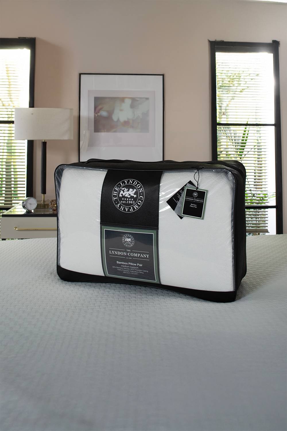 Bamboo soft pillow pair in white, featuring hallowfibre filling for medium support, packaged in a black and white zippered case with a tag, set against a soft interior backdrop.