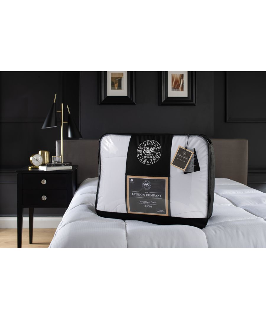 White duck down duvet by The Lyndon Company, 10.5 tog, double size, neatly packaged with a black and white label, placed on a dark background with a bedside table and lamp.
