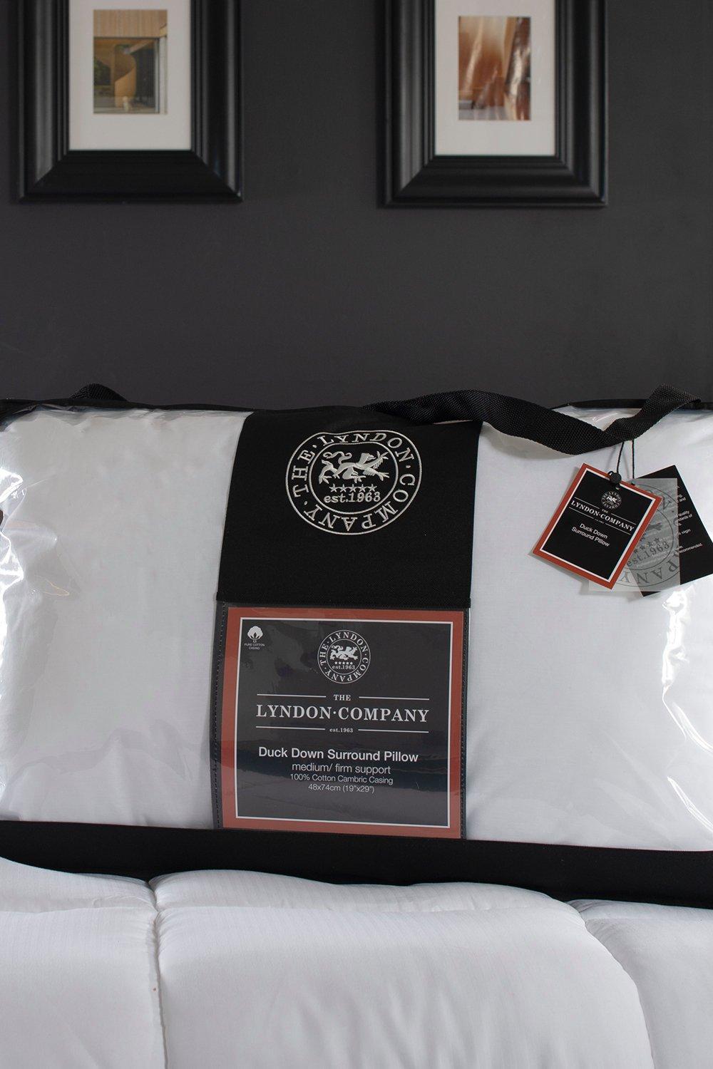 White pillow with duck down filling, medium to firm support, encased in a clear plastic packaging with a black label featuring The Lyndon Company logo and tags.