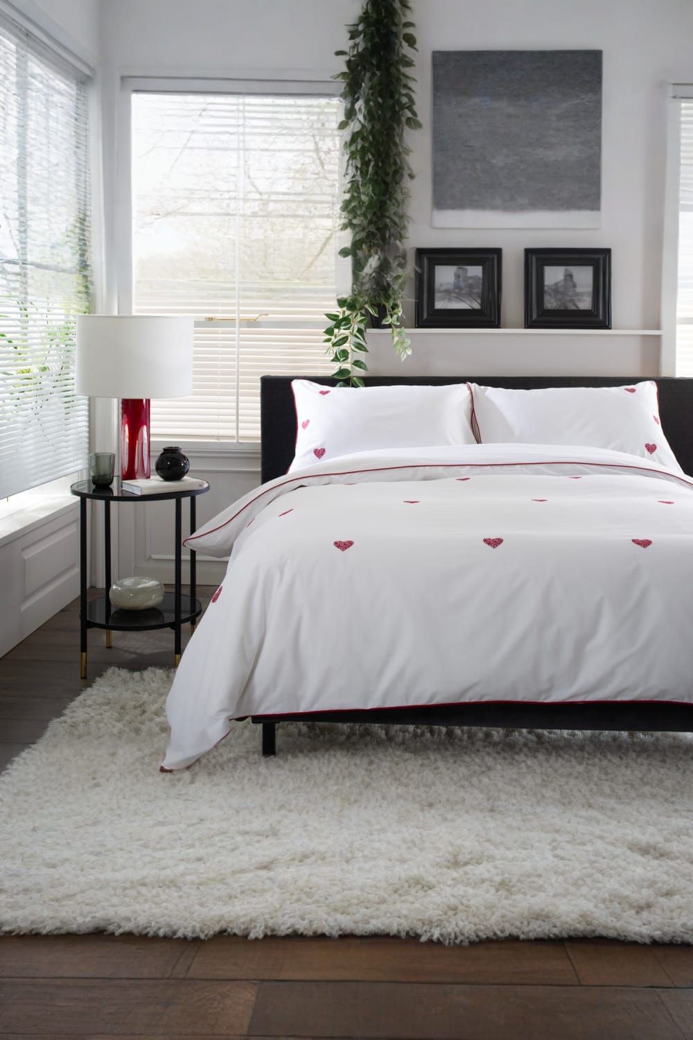 Elegant white duvet cover set with red embroidered hearts, made from 100% cotton, complemented by matching pillowcases, styled in a modern bedroom setting.