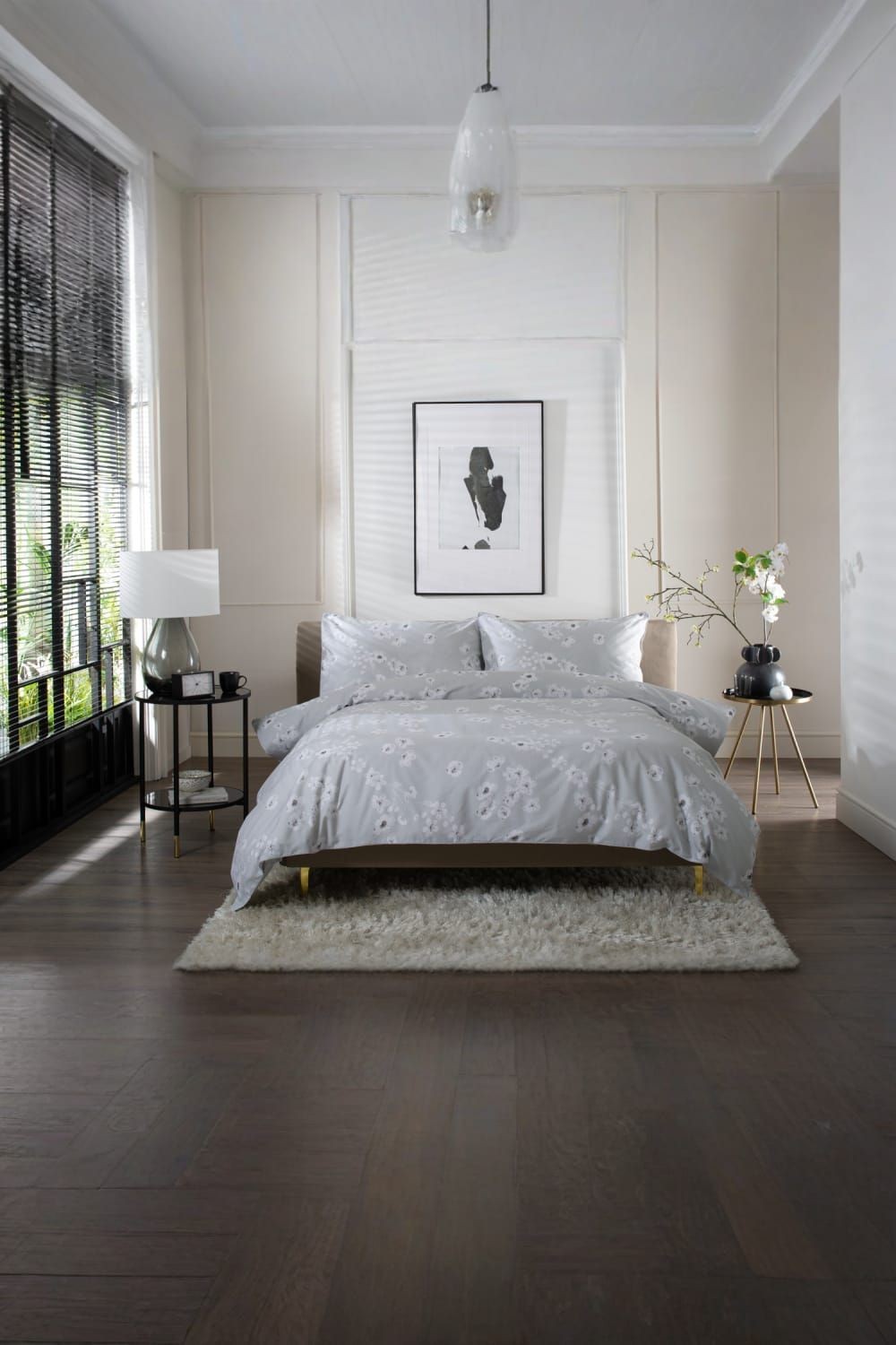 Petite Fleure printed duvet cover set in grey, made from 100% cotton, features piped edges and is styled on a bed with a light rug and modern decor.