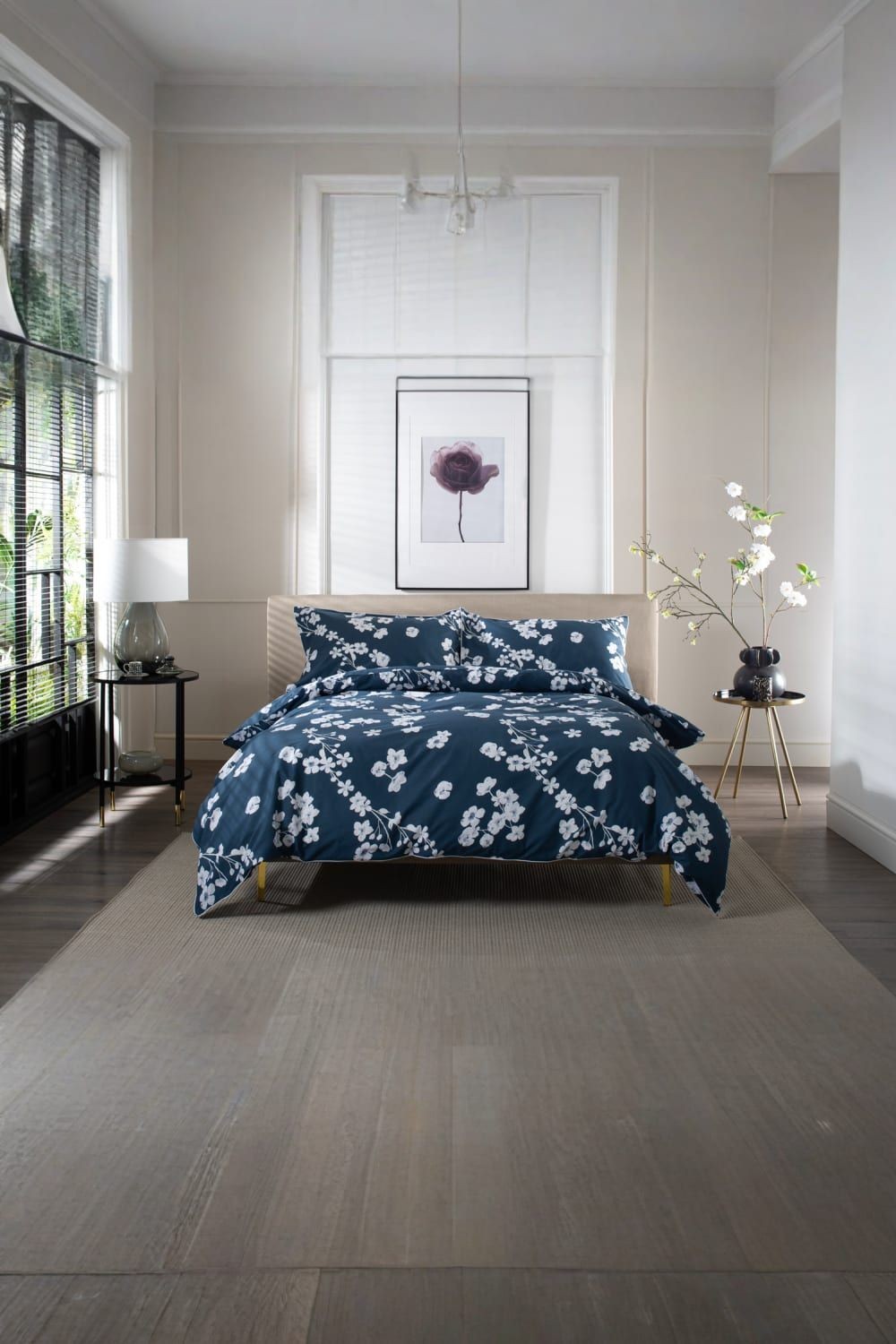 Navy cotton duvet cover set with white floral print and piped edges, displayed on a bed in a modern room with natural light and minimalist decor.