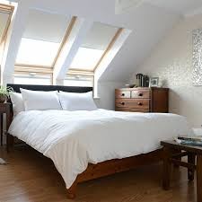 White super king duvet with a 240 thread count casing, featuring a plush goose feather and down fill, neatly arranged on a wooden bed in a bright, airy bedroom.