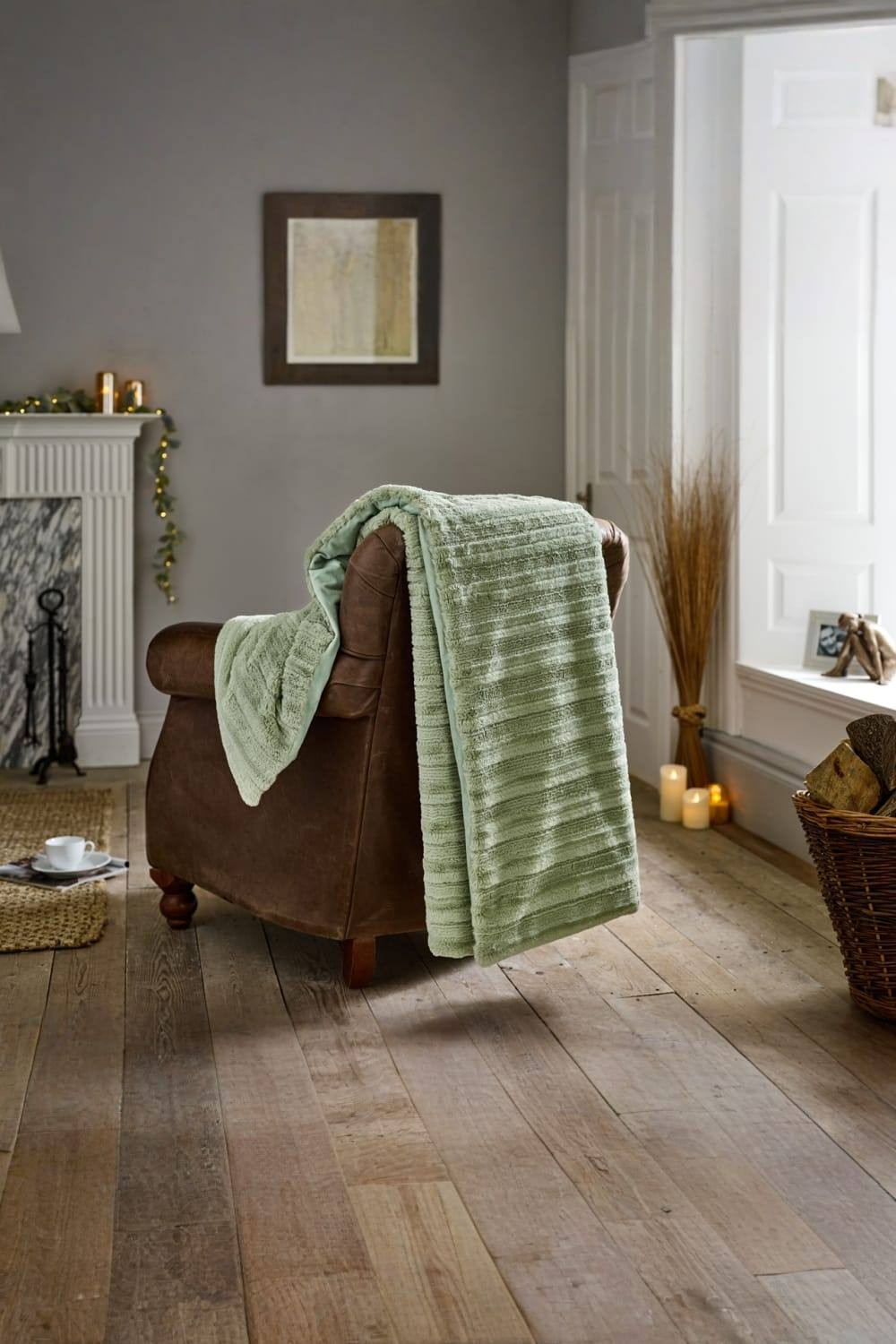 Soft green faux fur throw draped over a brown armchair, featuring a textured design, measuring 130x170cm, set in a cozy living room with warm lighting and natural decor.