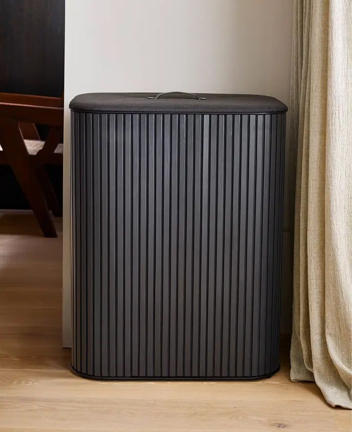 Black bamboo laundry basket with a ribbed design, featuring a lid and a handle, designed for 45 liters of laundry, set against a neutral interior backdrop.