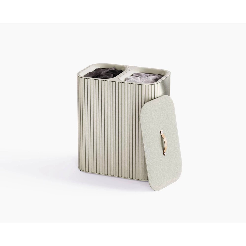 Bamboo laundry separation basket in light beige with a textured ribbed design, featuring two compartments and a lid with a stylish handle.