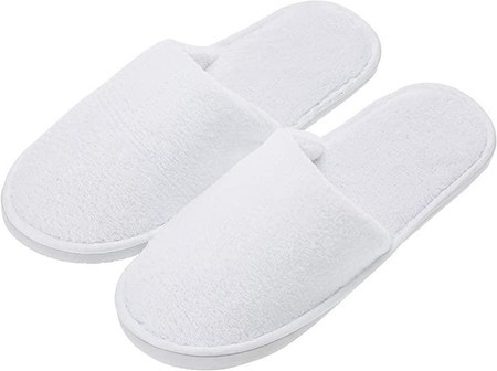White towelling hotel slippers with a soft, plush texture and a simple slip-on design, featuring a durable white rubber sole.