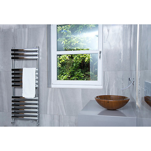 Chrome towel warmer with a sleek, modern design, featuring horizontal bars and a white towel hanging, set against a grey marble wall and a wooden basin.