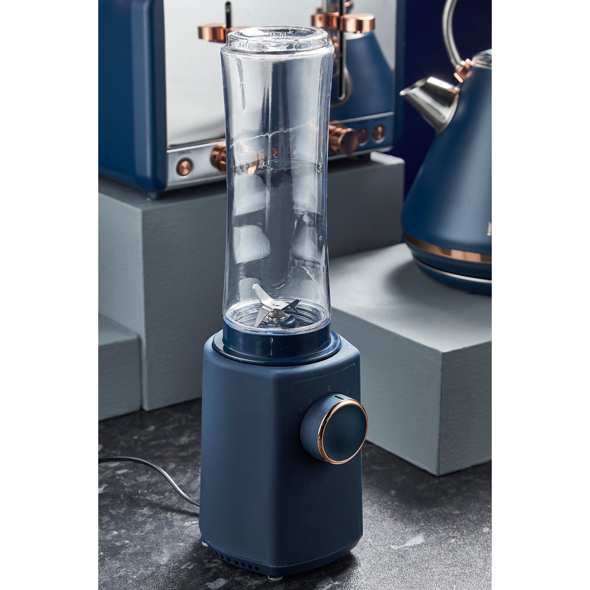 Grey personal blender with a tall, transparent blending jar, metallic accents, and a control knob, featuring a sleek design ideal for smoothies and quick blending.