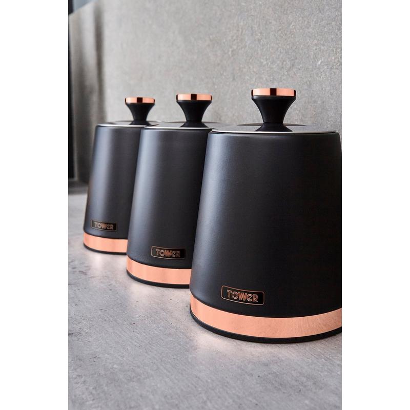 Three sleek kitchen canisters in matte pink with rose gold accents, featuring a stylish lid and the Tower logo on the front, set against a textured gray background.
