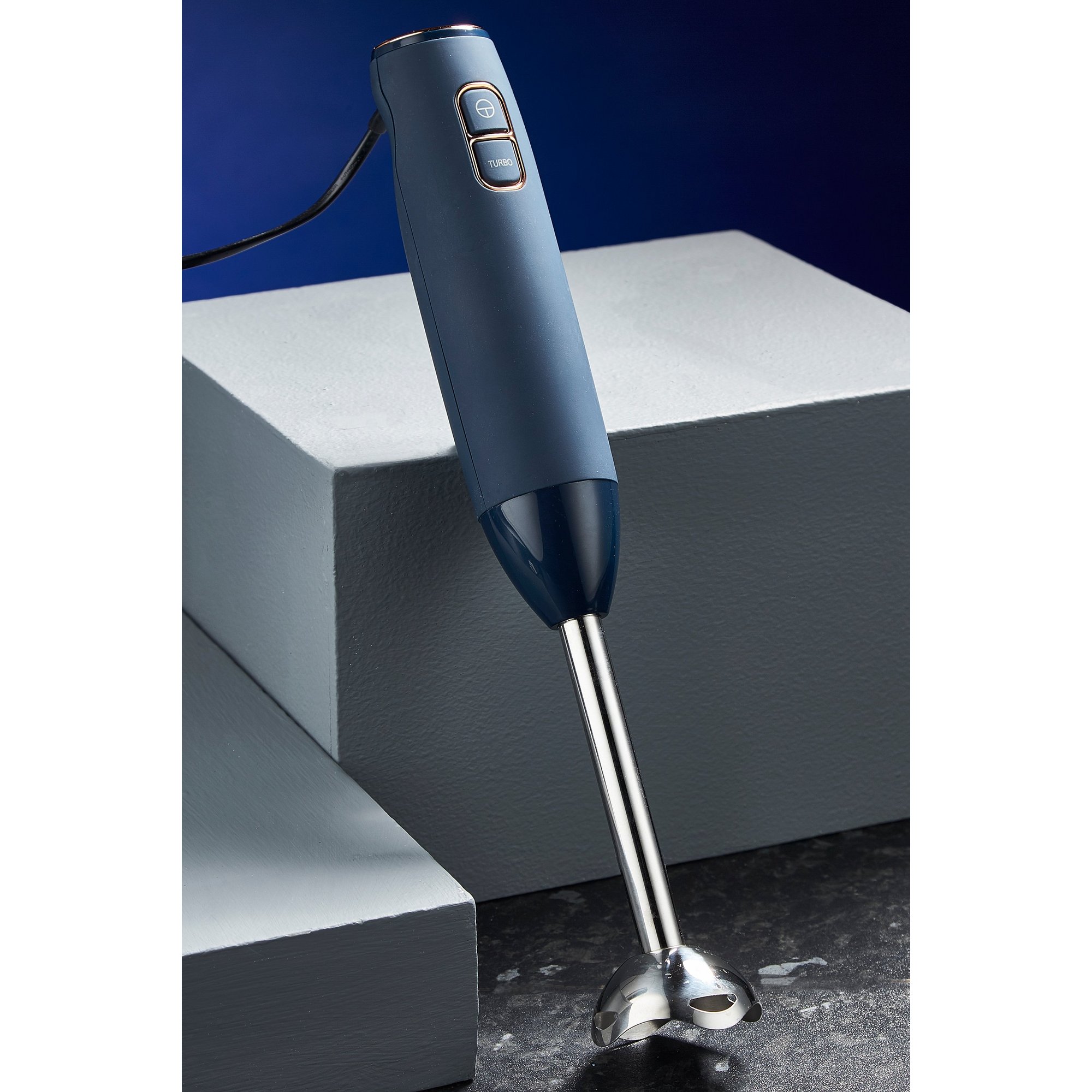 Blue Tower Cavaletto 600W stick blender with a sleek design, featuring a stainless steel blending shaft and two control buttons on the handle, placed on a textured surface.