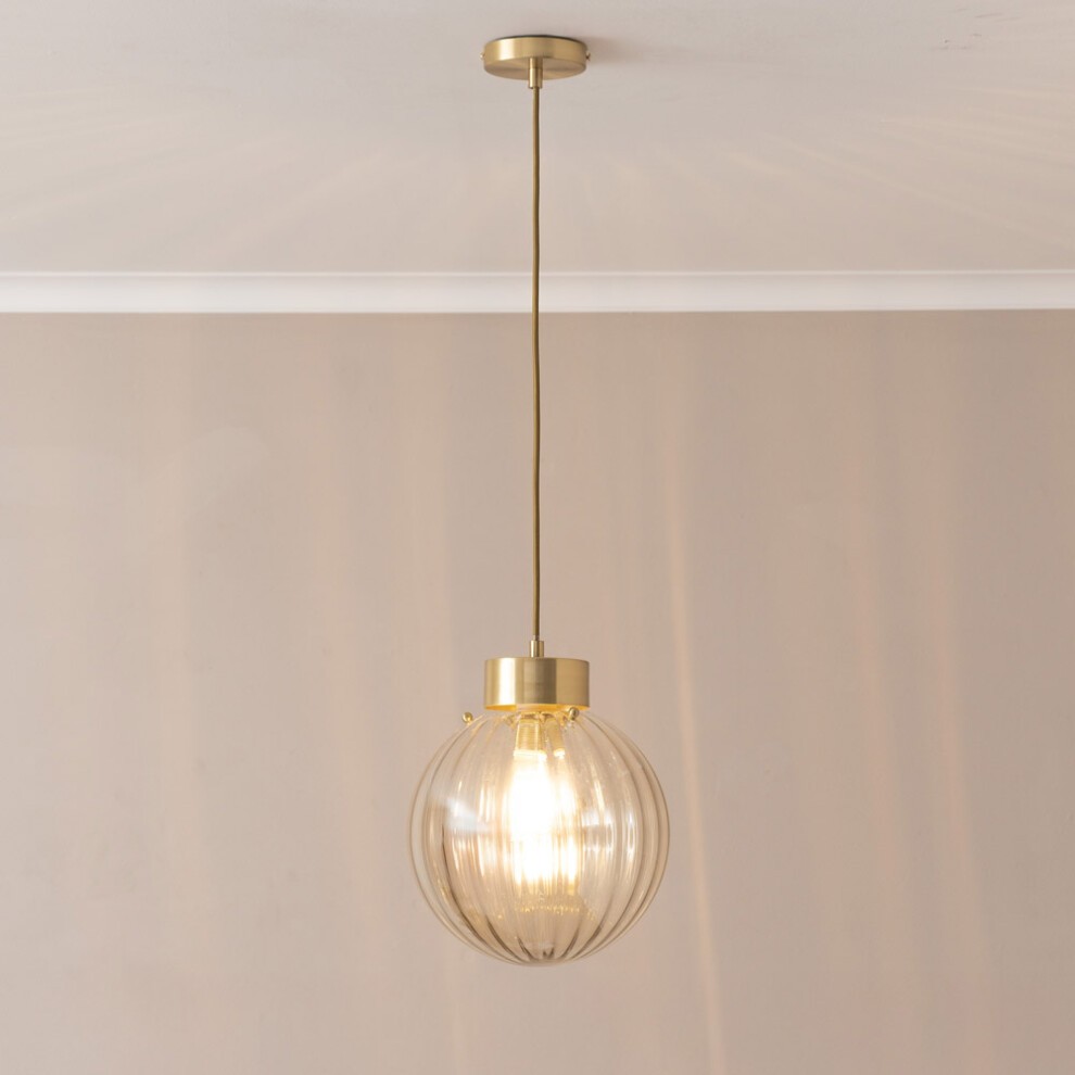 Brushed gold capped ceiling pendant light featuring a ribbed amber glass globe and a visible bulb, suspended from a sleek gold chain against a neutral background.