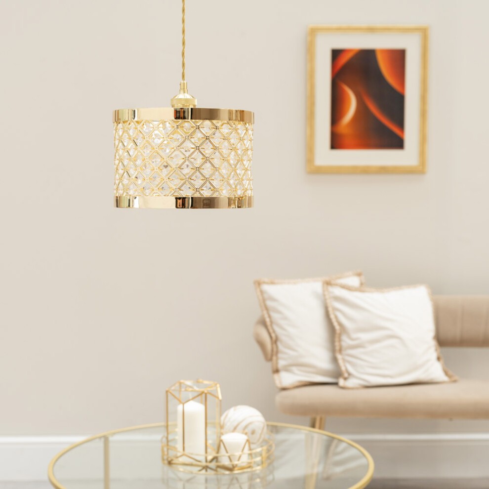 Gold multi-drum pendant light with a diamond-patterned shade, featuring a polished finish, hanging above a glass table with decorative items and a neutral-toned sofa.