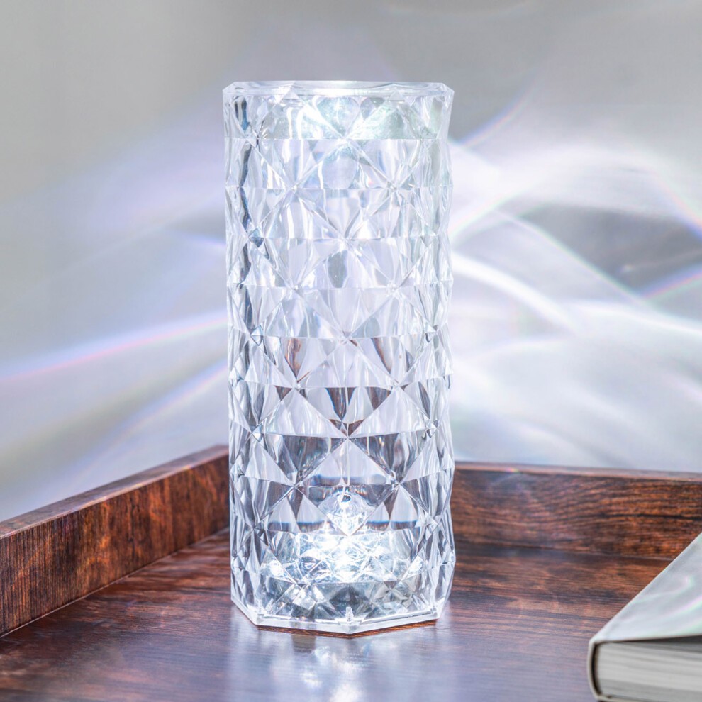 Crystal-style desk lamp with a faceted design, featuring RGB color change and remote control, displayed on a wooden surface with a soft glow in pink hues.