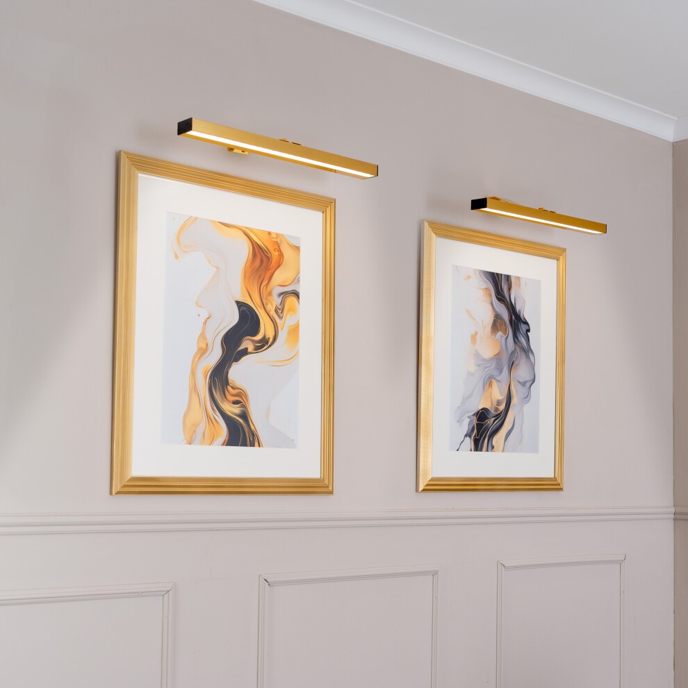 Two gold rechargeable wall touch light fittings mounted above framed abstract art, featuring fluid orange and black designs on a neutral wall.