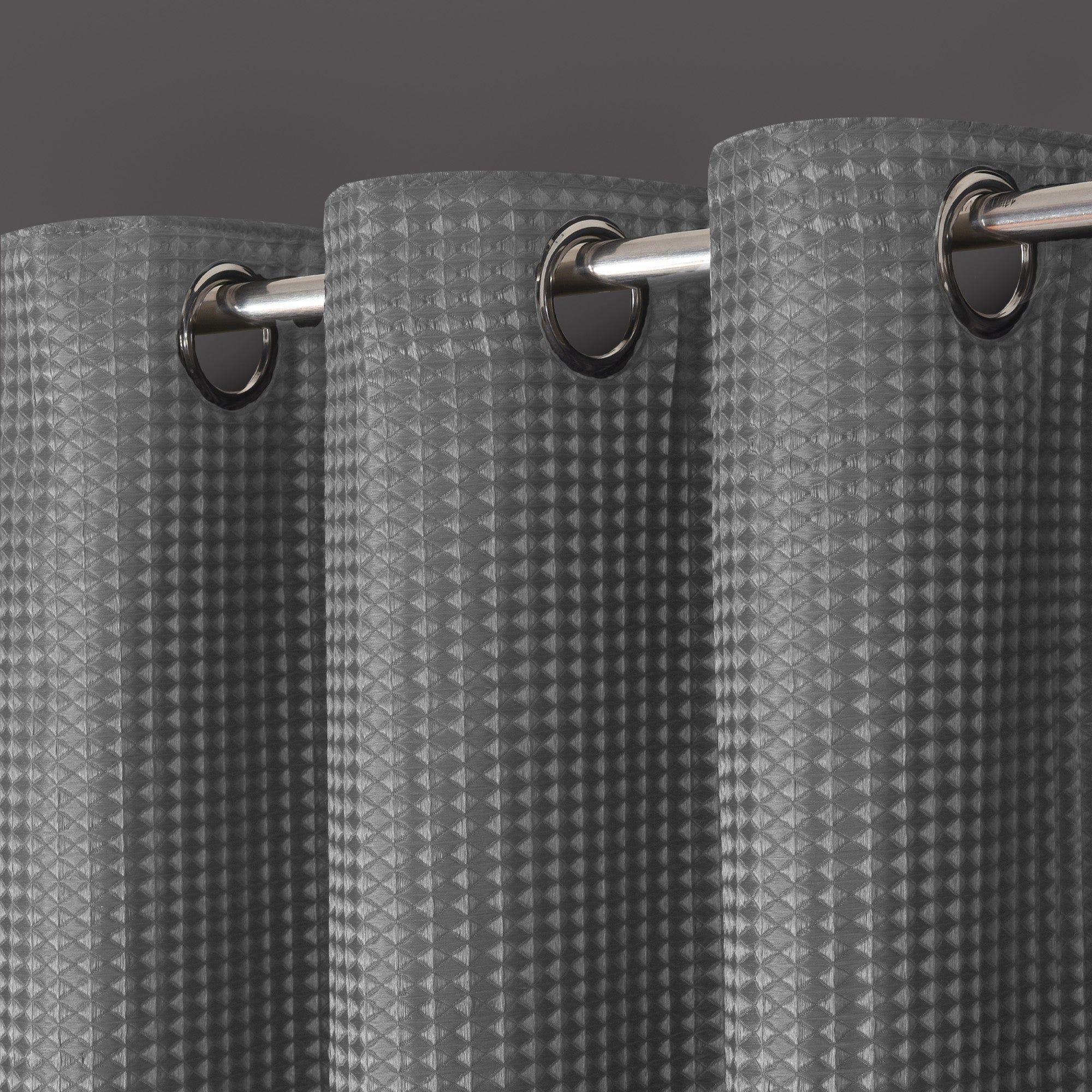 Total blackout curtains in a textured waffle weave design, featuring a dark gray color and eyelet header for easy hanging with a sleek metallic finish.