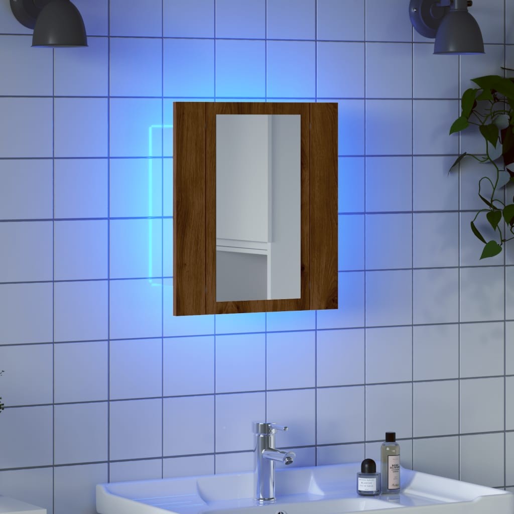 LED bathroom mirror cabinet in artisan oak finish, featuring a rectangular mirror, illuminated edges, and mounted on a tiled wall above a modern sink with toiletries.