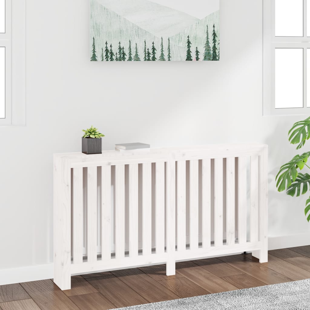 White radiator cover made of solid pine wood, measuring 153x19x84 cm, featuring slatted design and placed against a light wall with a plant and artwork above.