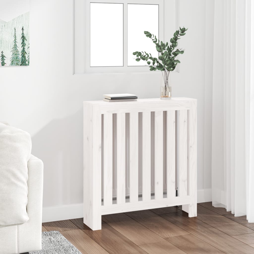 White solid wood radiator cover with slatted design, measuring 79.5x19x84 cm, placed beside a sofa in a bright room with a window and decorative plant.