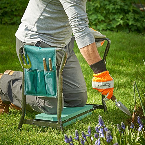 Garden kneeler seat in green and black with a padded cushion, featuring a tool set including a trowel and gloves, positioned on grass with purple flowers nearby.