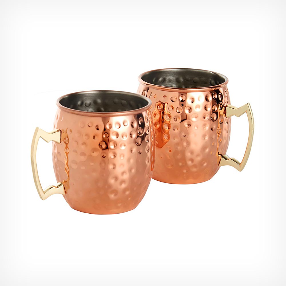 Two hammered copper Moscow mule mugs with a shiny finish and gold-tone handles, showcasing a distinctive dimpled texture.