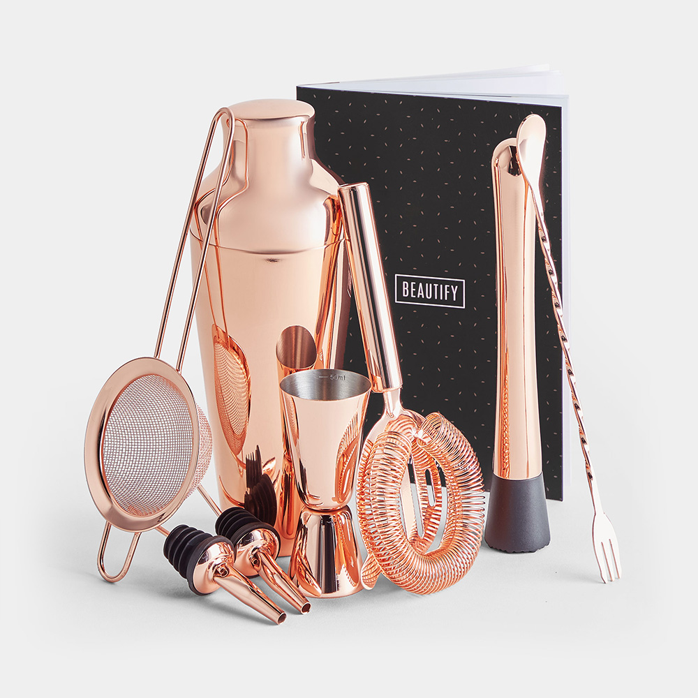 Copper cocktail set featuring a shaker, strainer, jigger, stirring stick, pour spouts, and a recipe book, all with a sleek, polished finish.