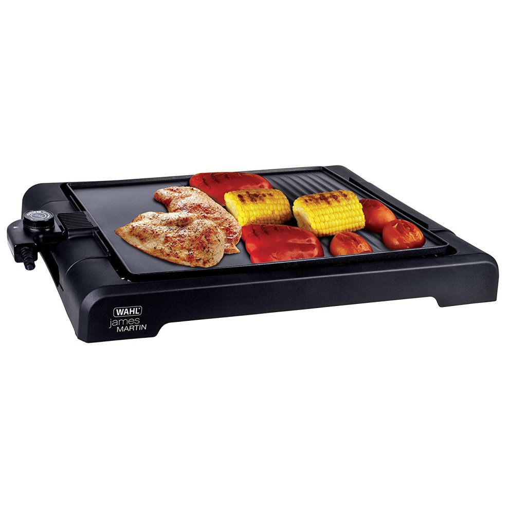 Black Wahl James Martin Table Top Health Grill features a flat cooking surface with grilled chicken, corn, tomatoes, and peppers, showcasing a sleek design and adjustable temperature control.