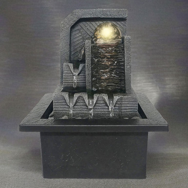 Grey Aztec-style water fountain featuring a spinning golden ball, textured stone-like tiers, and a square base with flowing water accents.
