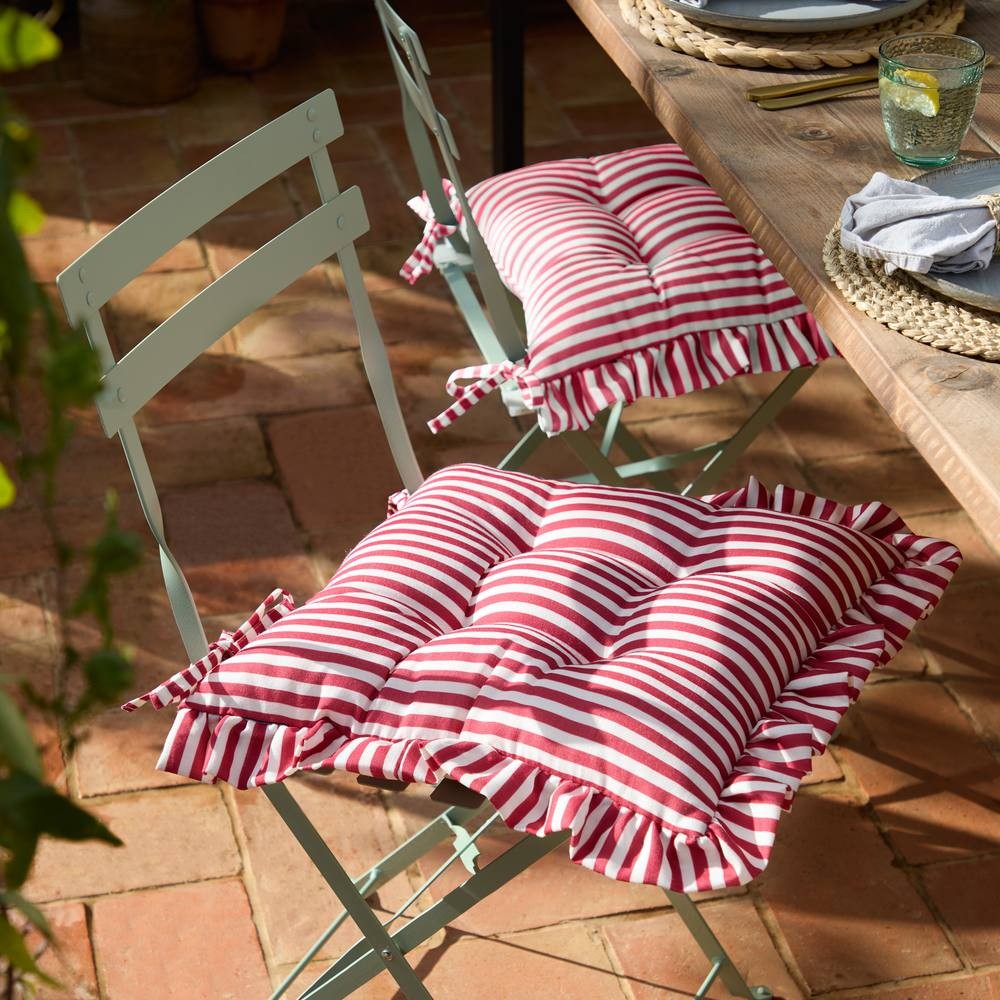 Red and white striped ruffle seat pads in a 2-pack, made of soft fabric, designed for indoor or outdoor use, featuring ties for secure attachment to chairs.