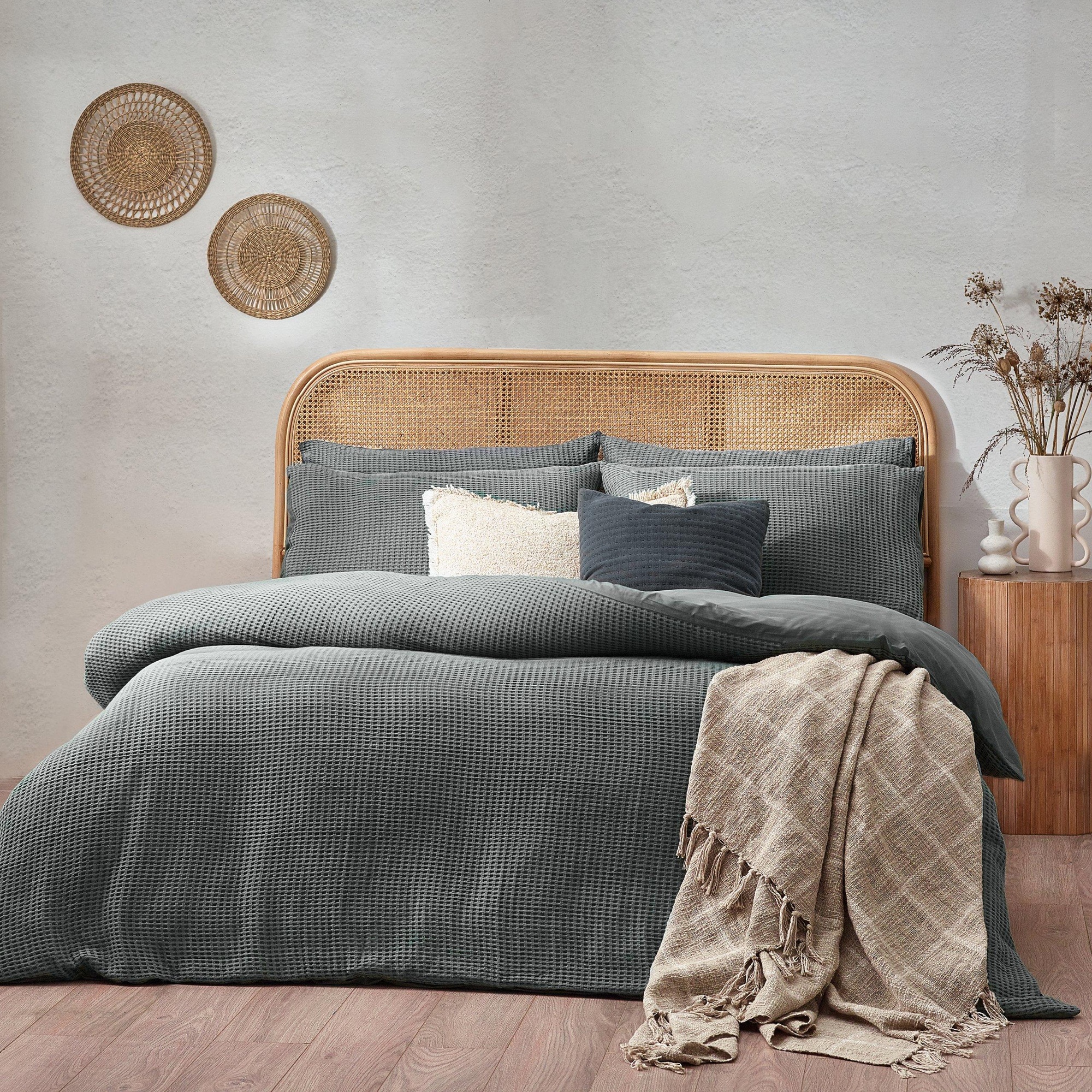 Chunky waffle textured duvet cover set in blue, made of 100% cotton, featuring a double size with matching pillowcases, styled with a woven headboard and decorative elements.