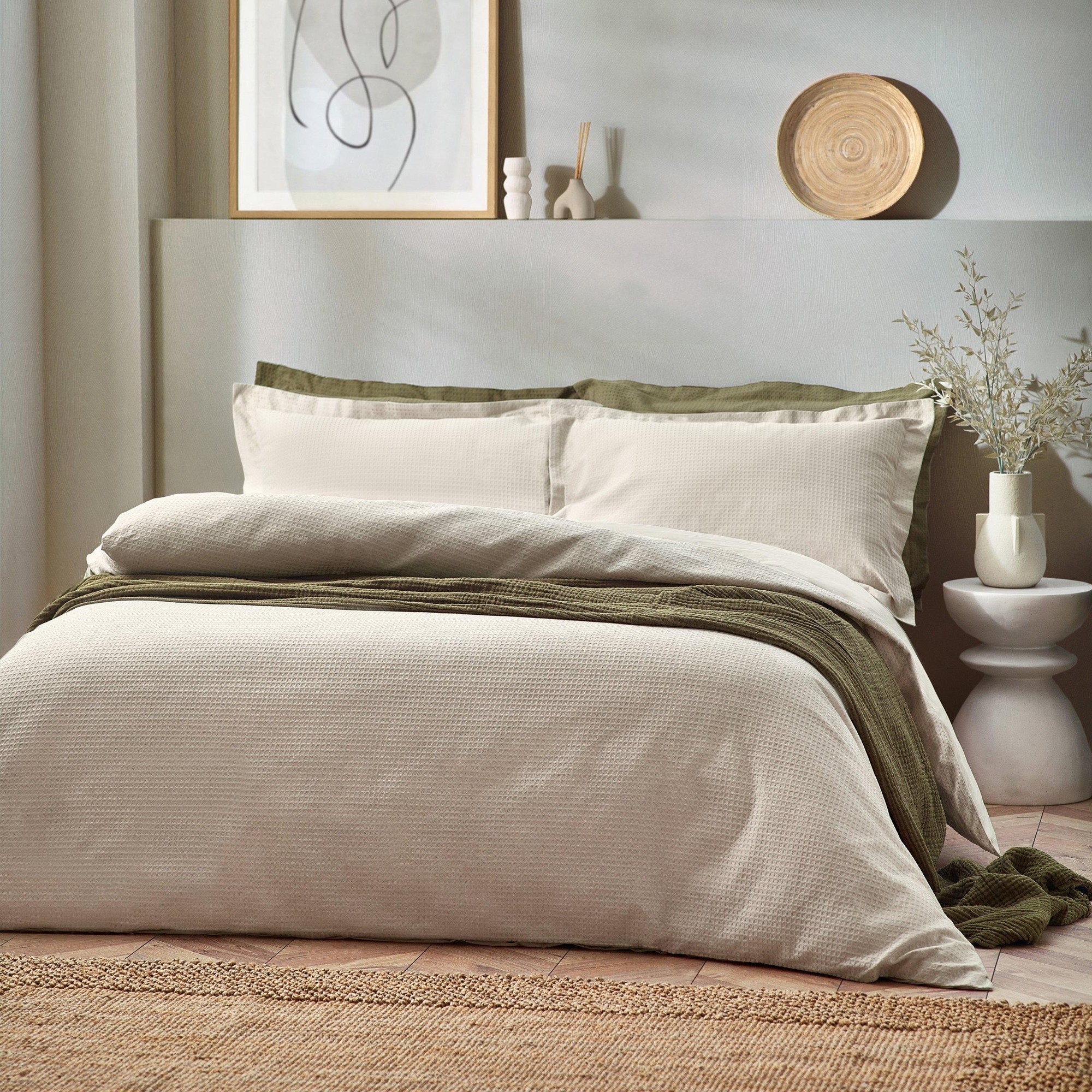 Beige cotton duvet cover set with a waffle texture, featuring a double size, complemented by green accent pillows and a textured throw on a styled bed.