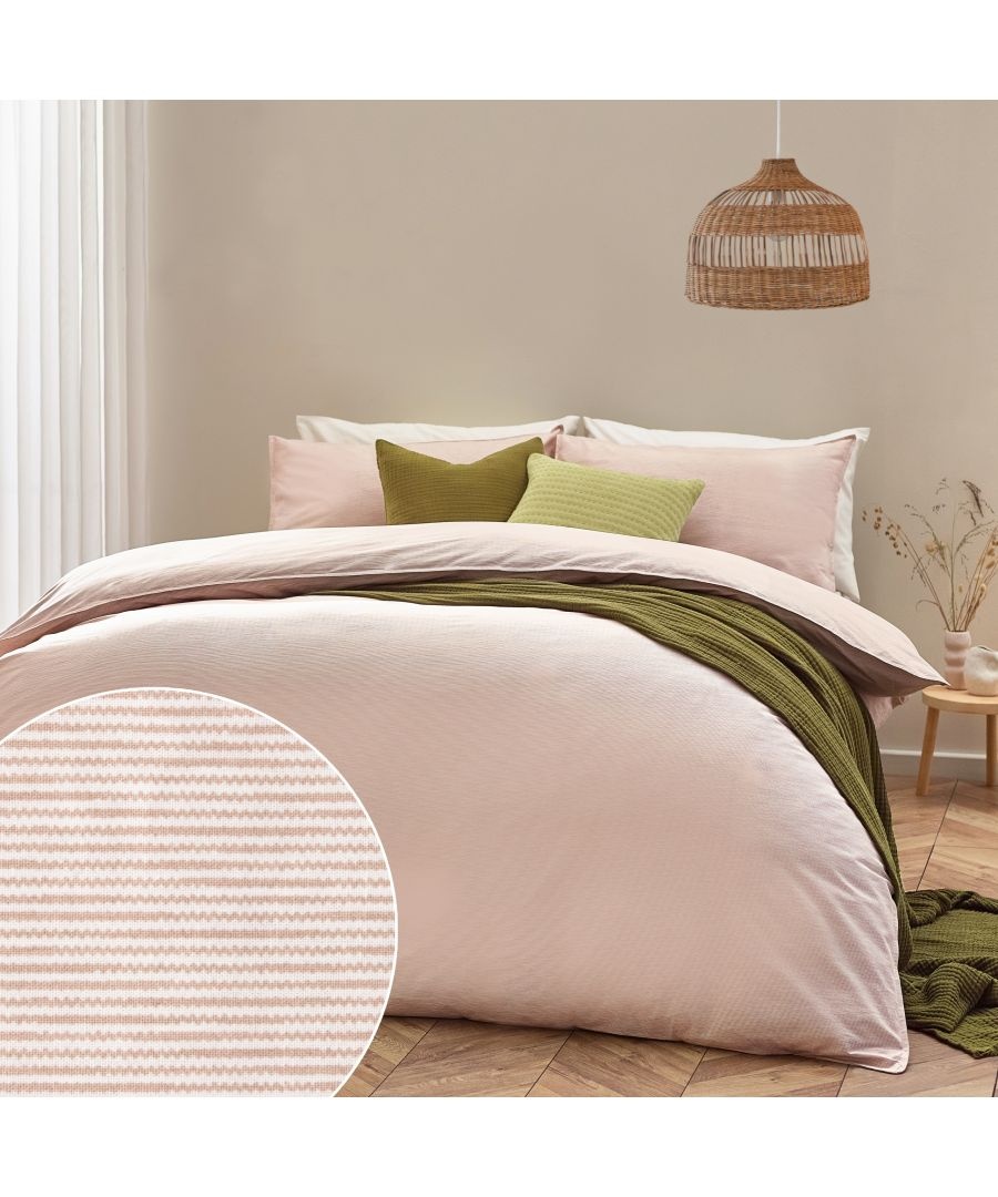 100% cotton king duvet cover set in baked earth tones with subtle stripes, complemented by green and beige pillows, set against a light, airy room with wooden accents.