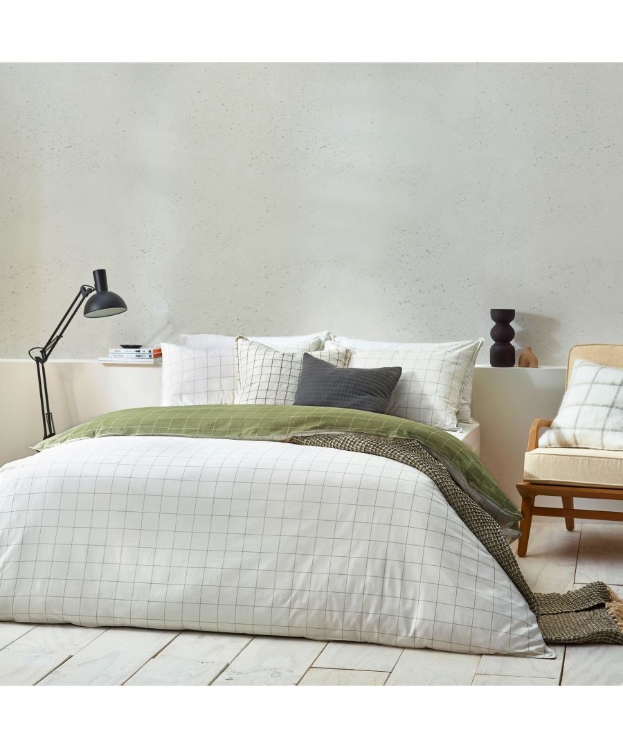 Yard Howarth Check Reversible Duvet Cover Set in natural cotton features a grid pattern in white and green, styled with coordinating cushions and a minimalist lamp in a cozy bedroom setting.